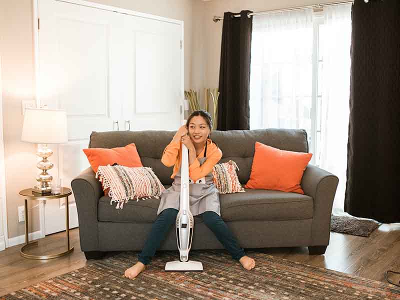 Woman sitting on sofa with vacuum cleaner