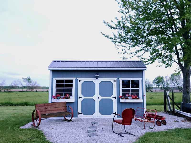 Blue garden shed with white trim in a rock garden