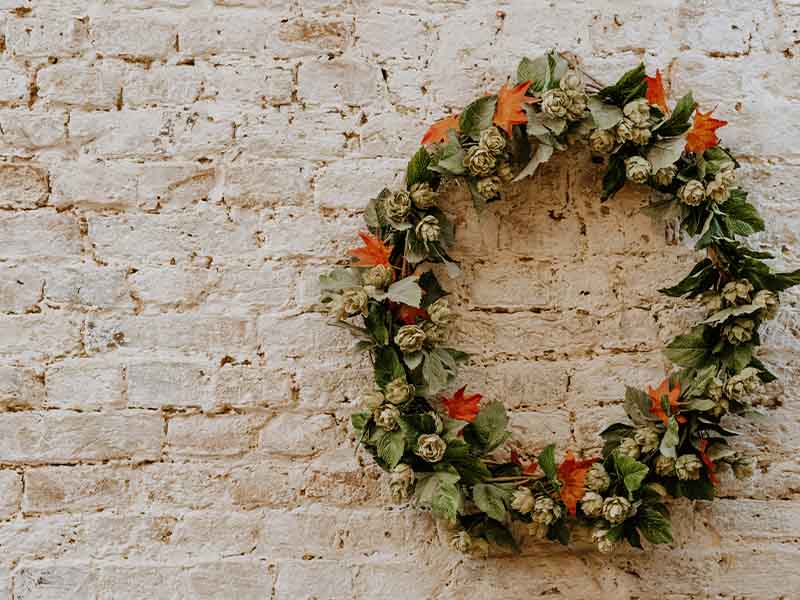 Orange and green wreath on a white brick wall