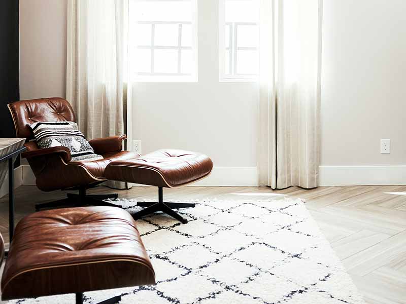 Black and white decor in a modern living space with brown leather chair and white rug