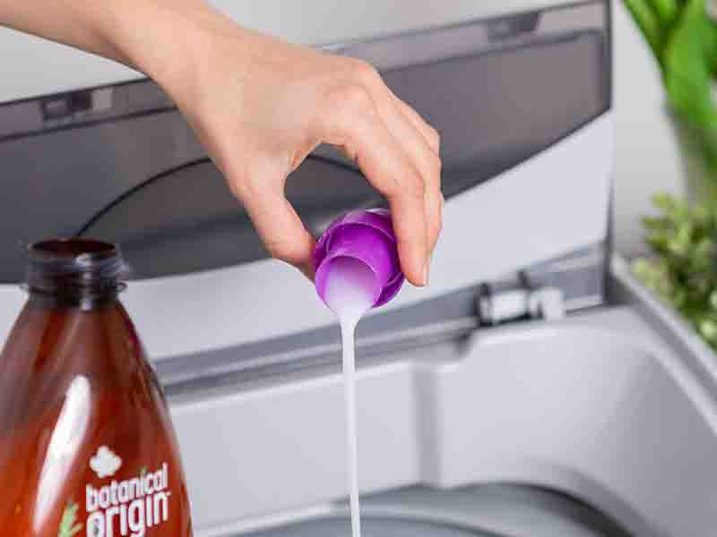 Woman putting detergent into washing machine