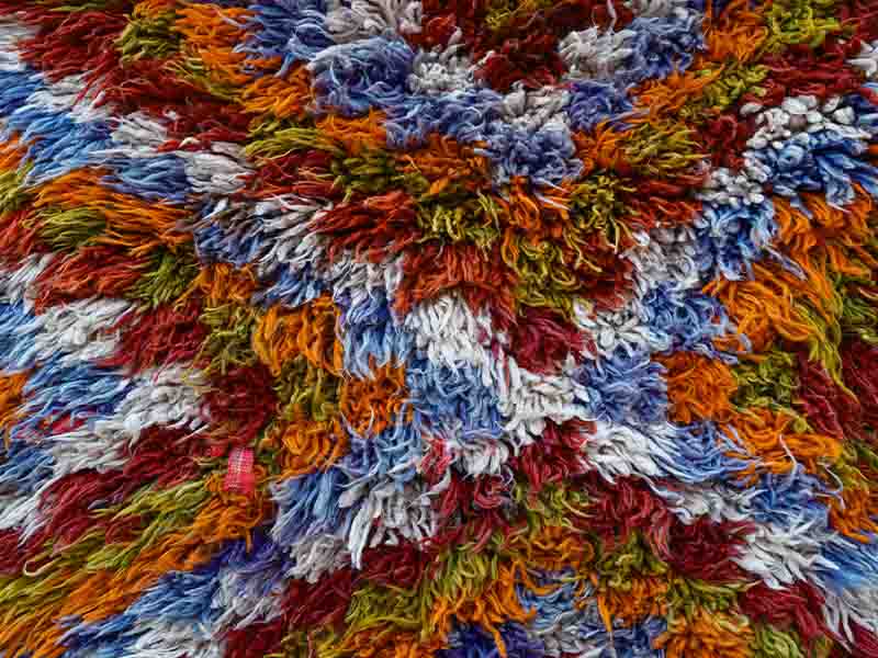 Close up shot of a thick textured rug with lots of color