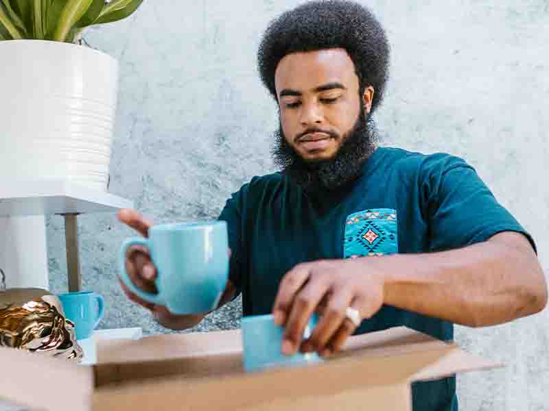 Man packing coffee mugs in box