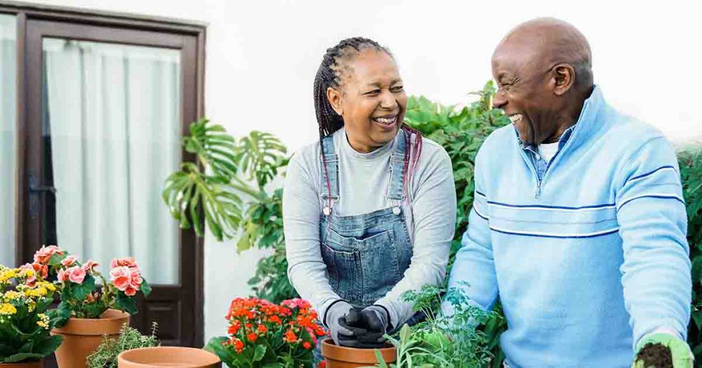 Couple potting plants and smiling