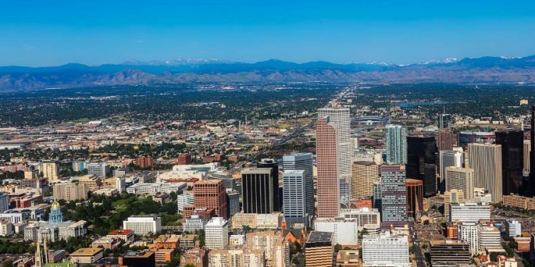 Aerial view of Downtown Denver with high-rise buildings, tree-lined streets, and mountains visible in the distance, surrounded by some of the best Denver neighborhoods.