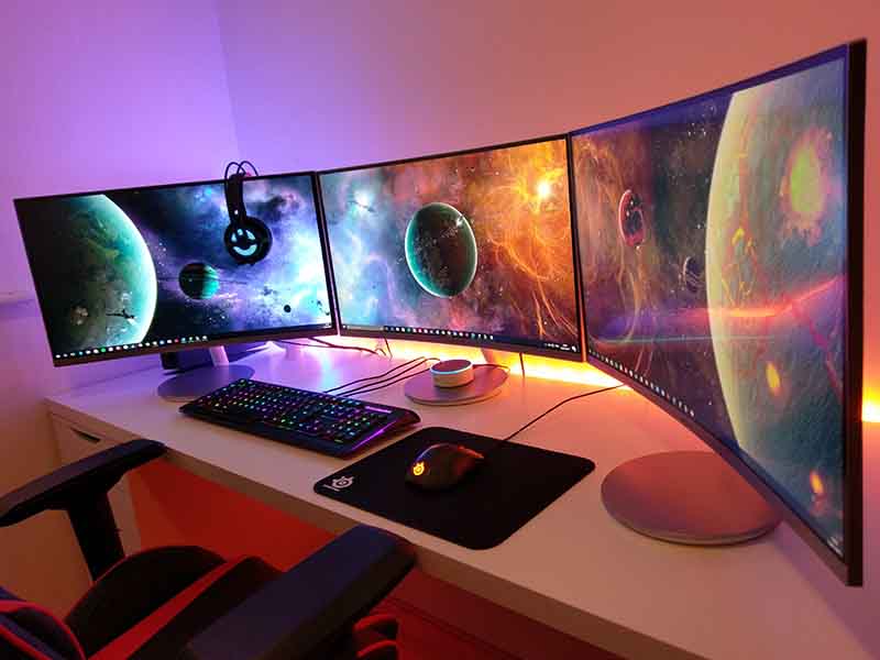 Large gaming set up with computer monitors on white desk