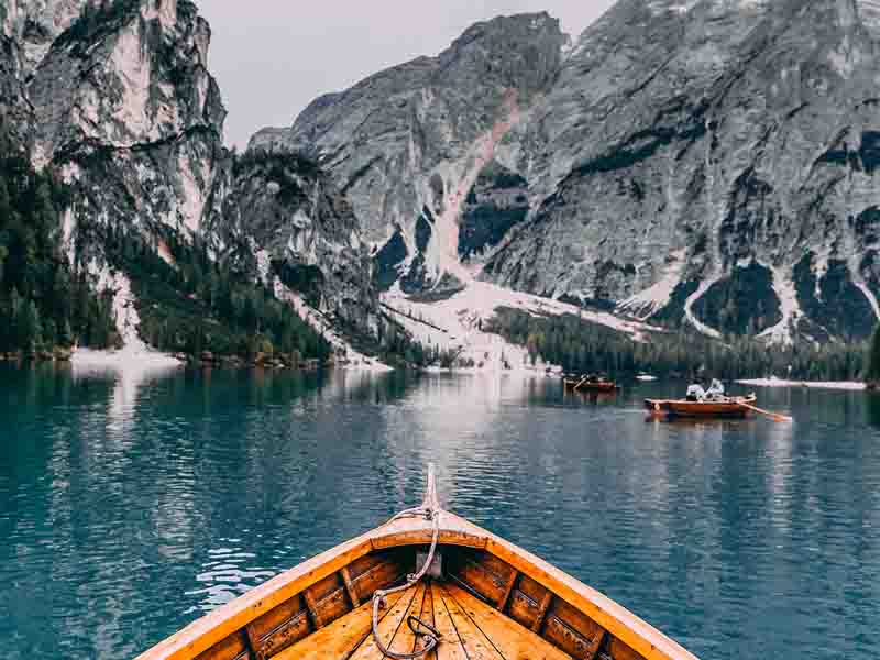 Boat in a lake surrounded by snow covered mountains