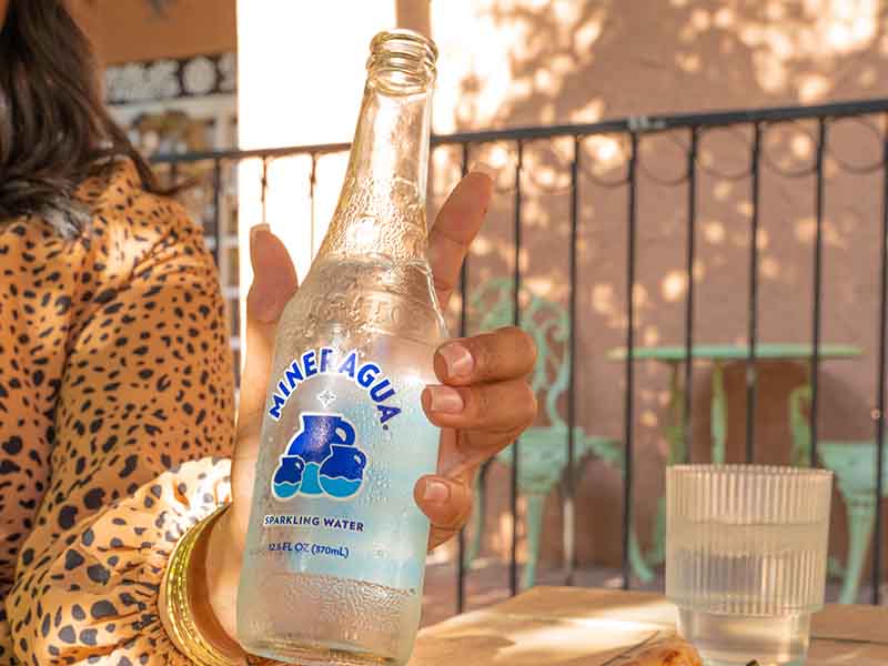 Woman holding mineral water bottle at lunch