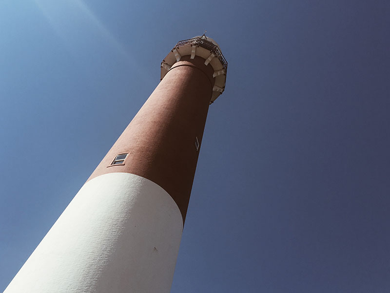 Red and White Barnegat Lighthouse shot from below in a sunny sky.
