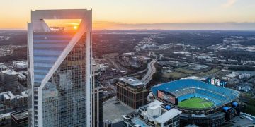 The Charlotte city skyline at sunset featuring Uptown high-rises and Bank of America Stadium, a view that welcomes those moving to Charlotte.