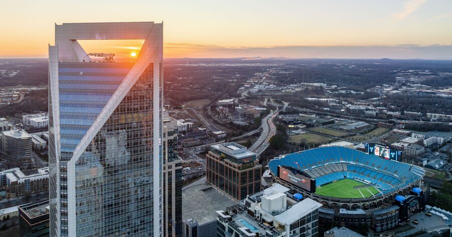The Charlotte city skyline at sunset featuring Uptown high-rises and Bank of America Stadium, a view that welcomes those moving to Charlotte.