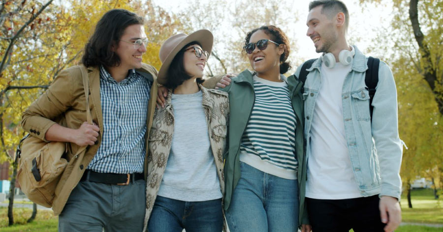 Friends walking together through a city park with open green spaces, like those found in Charlotte, North Carolina.
