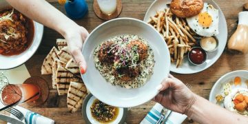 Friends share a variety of dishes at a popular dining spot, showcasing the best restaurants in Charlotte for groups and shared plates.