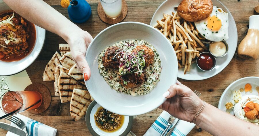 Friends share a variety of dishes at a popular dining spot, showcasing the best restaurants in Charlotte for groups and shared plates.