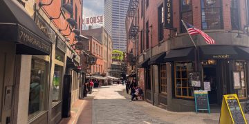 Sunny daytime view down Marshall Street featuring brick storefronts in Haymarket, one of the best neighborhoods in Boston for tourists to visit.
