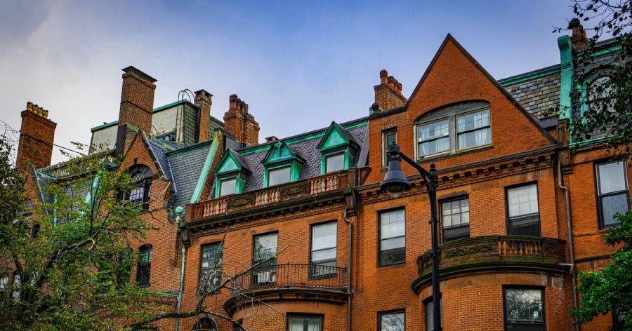 Exterior view of red-brick townhomes with green patina details in one of the best neighborhoods in Boston.