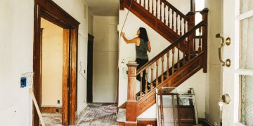 A woman is inspecting a wall in her house, which is mostly empty thanks to home renovation storage.